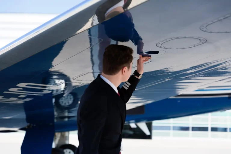 A pilot inspecting the underside of a wing to ready the business jet for takeoff.