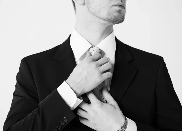 Close-up of a man in a suit adjusting his tie, symbolizing confidence and readiness for a professional career.